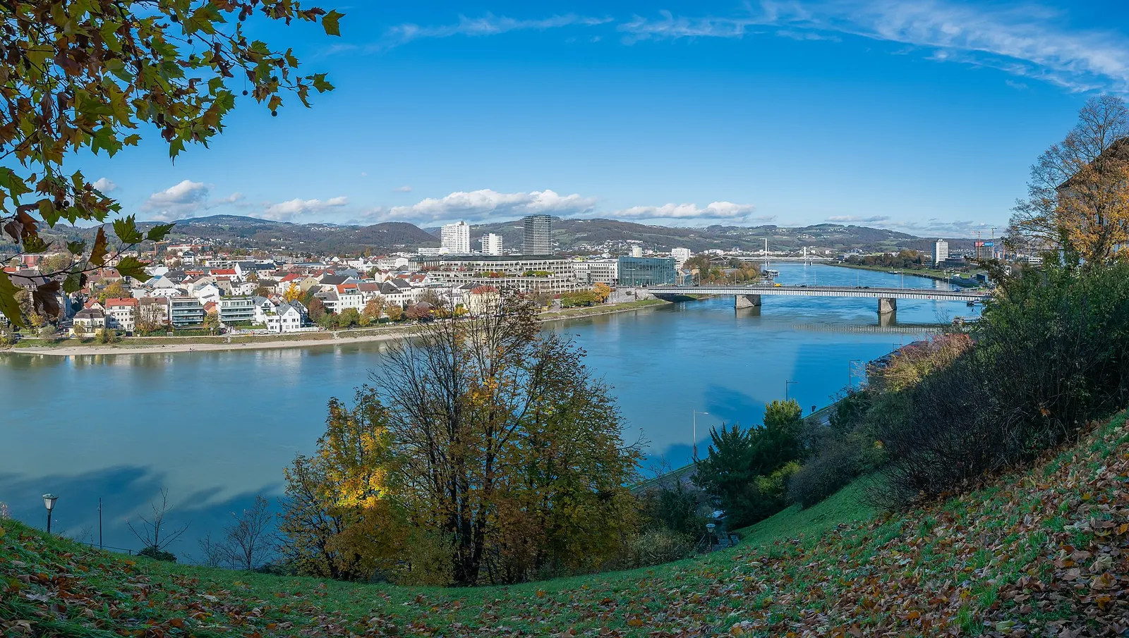 Paar spaziert am Abend an der Donaulände in Linz, im Hintergrund das beleuchtete Lentos Kunstmuseum