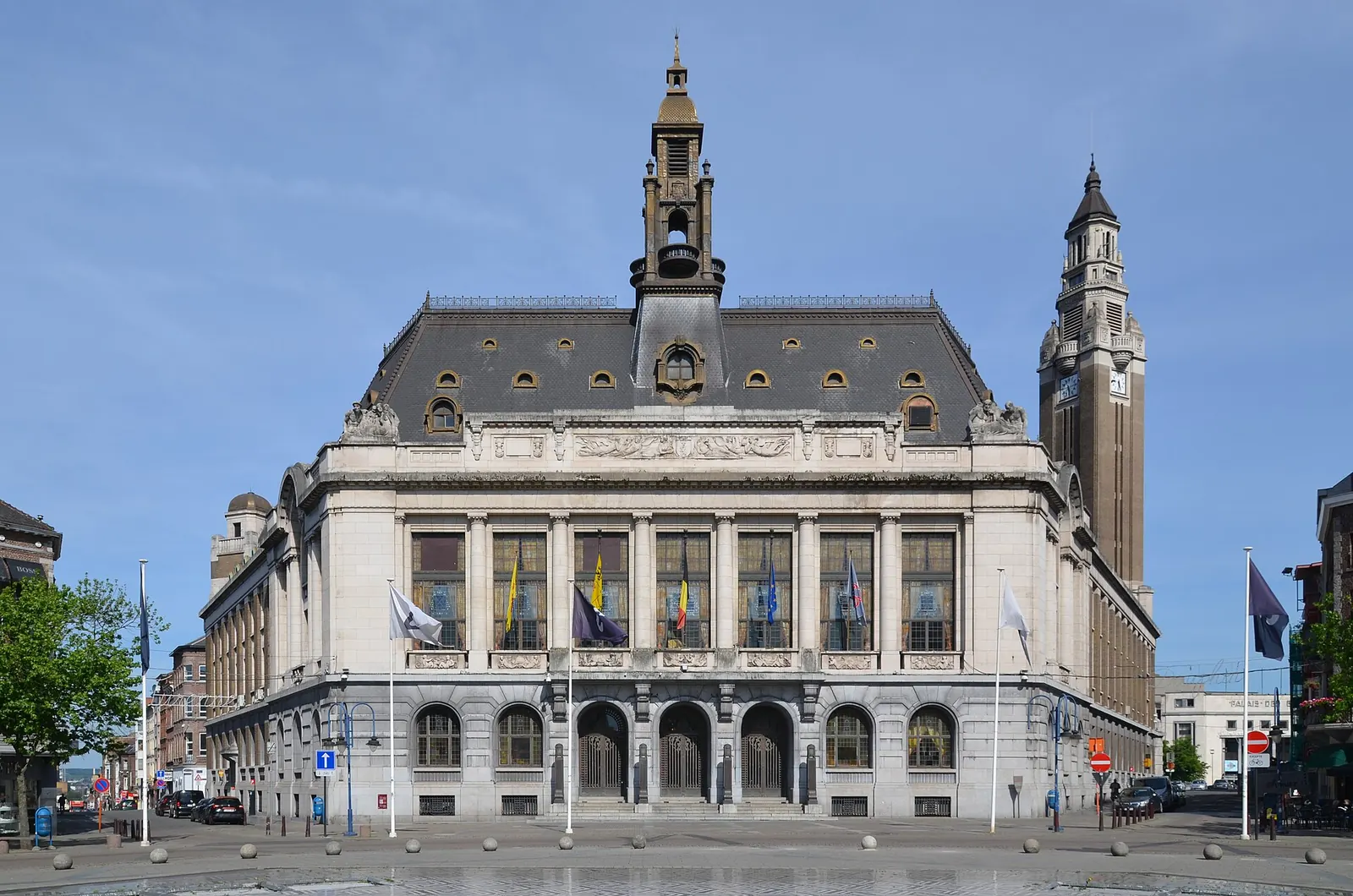 Deux personnes au sommet d'un terril couvert de végétation, avec Charleroi et ses toits en contrebas