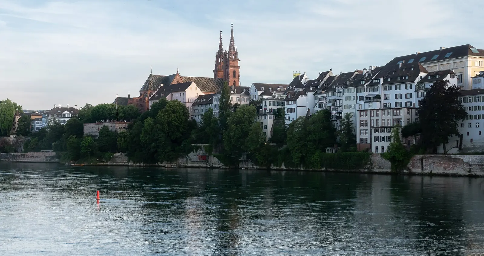 Zwei Menschen sitzen am Abend auf den Stufen am Kleinbasler Rheinufer, gegenüber das Basler Münster