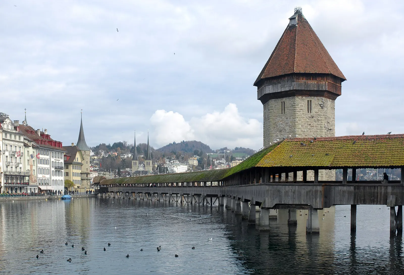 Paar spaziert über die Kapellbrücke in Luzern, im Hintergrund der Vierwaldstättersee und der Pilatus