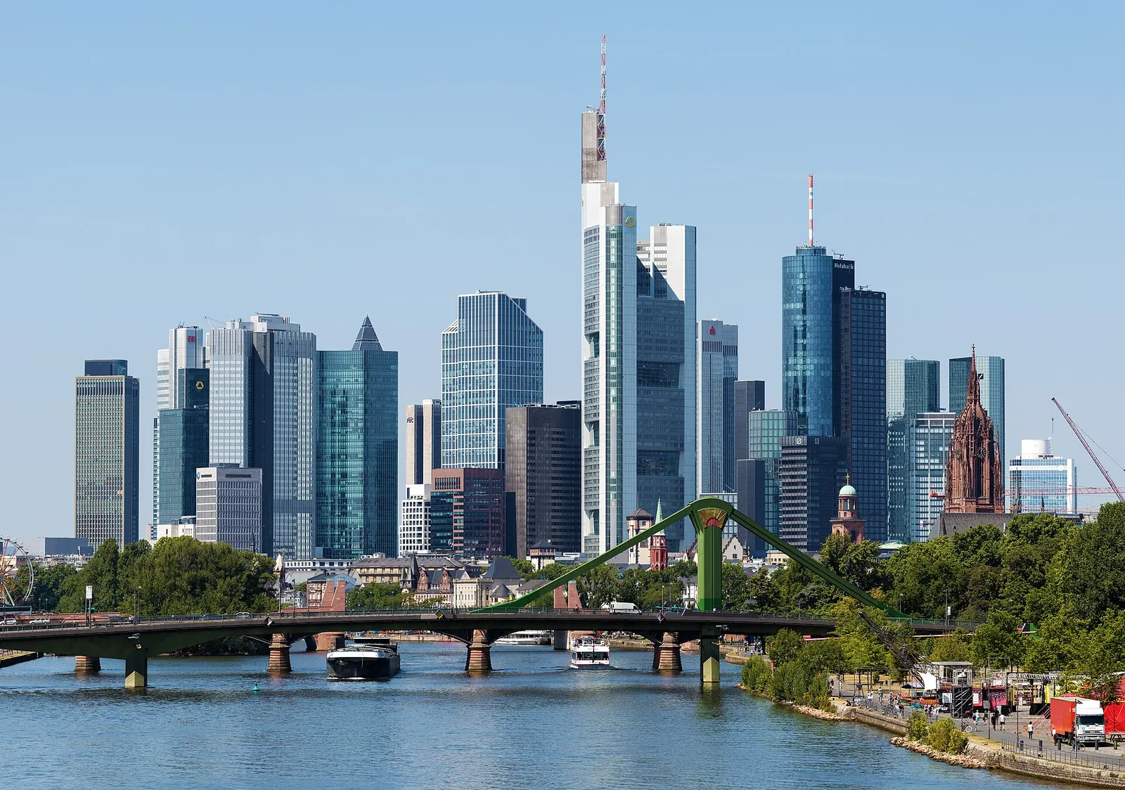Paar steht abends auf dem Eisernen Steg in Frankfurt, im Hintergrund die beleuchtete Skyline am Main