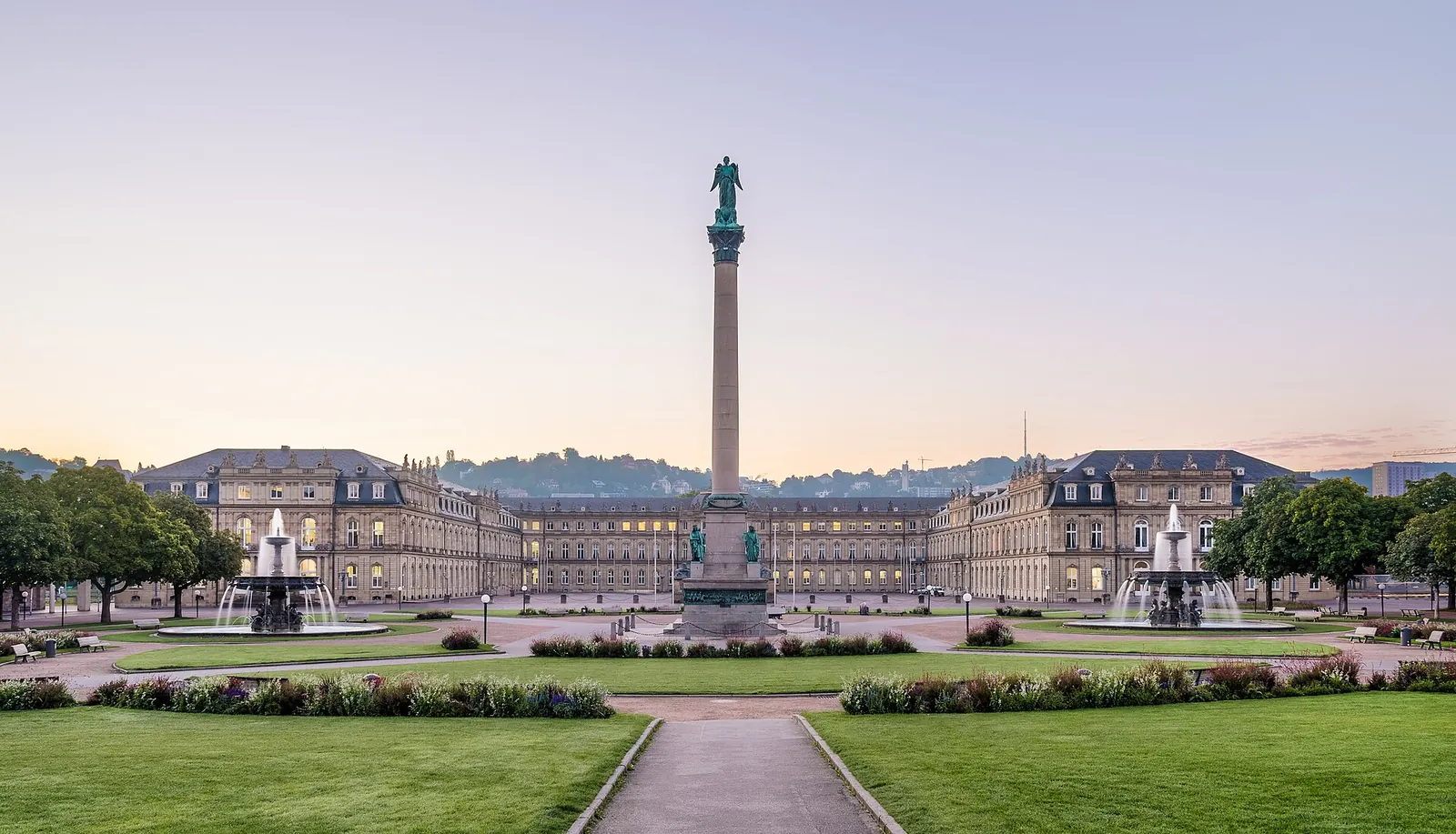 Paar sitzt auf einer Bank zwischen Weinreben oberhalb von Stuttgart und blickt über die Stadt im Talkessel
