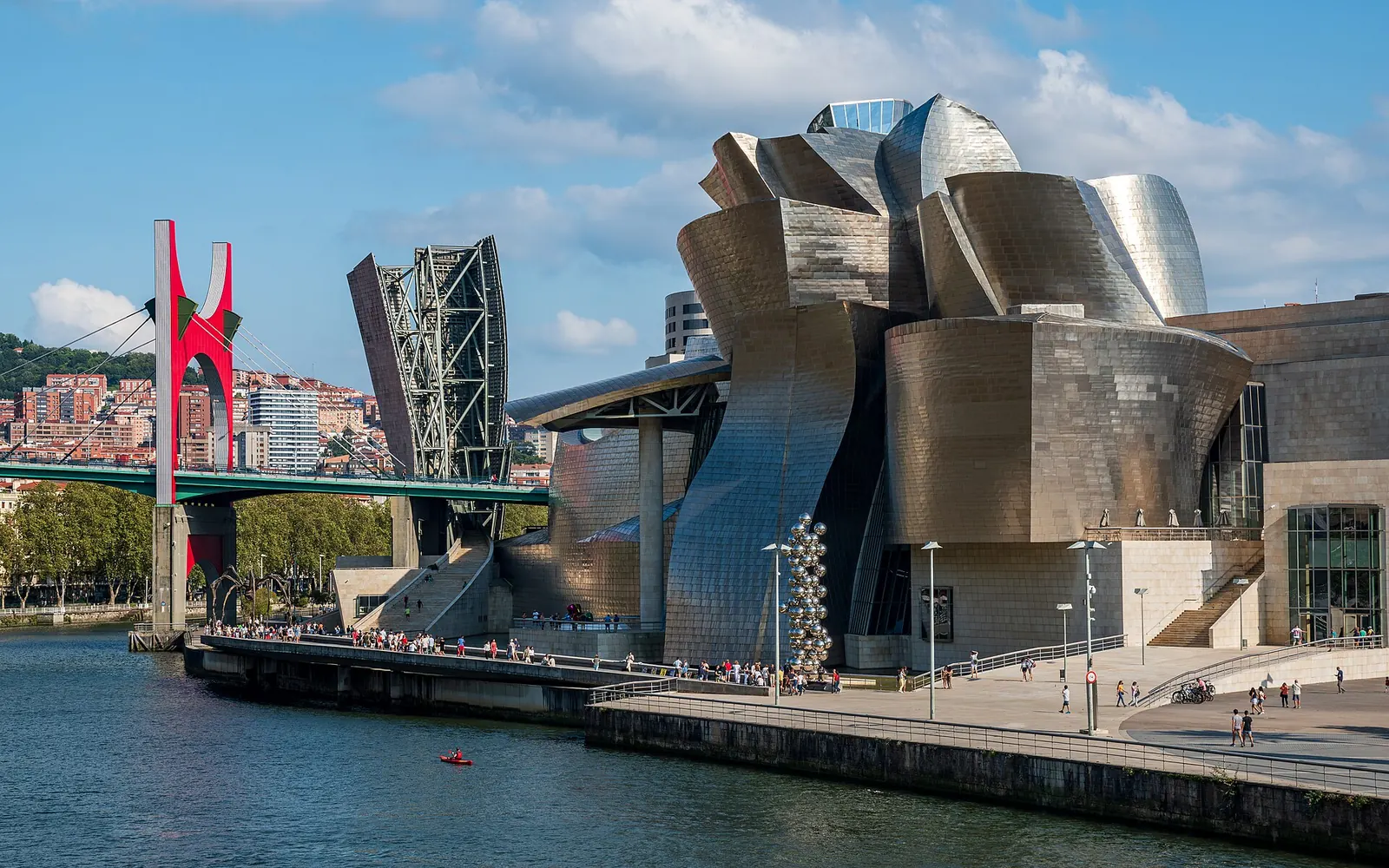 Pareja paseando junto a la ría de Bilbao con el museo Guggenheim al fondo