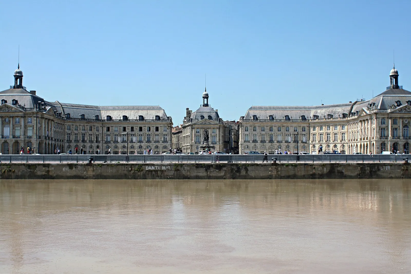 Couple qui marche pieds nus dans le miroir d'eau, face à la place de la Bourse, au crépuscule