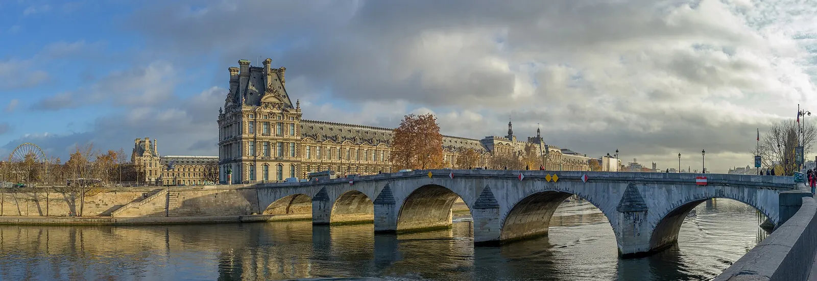 Couple qui marche le long des quais de Seine au coucher du soleil, avec l'île Saint-Louis en arrière-plan