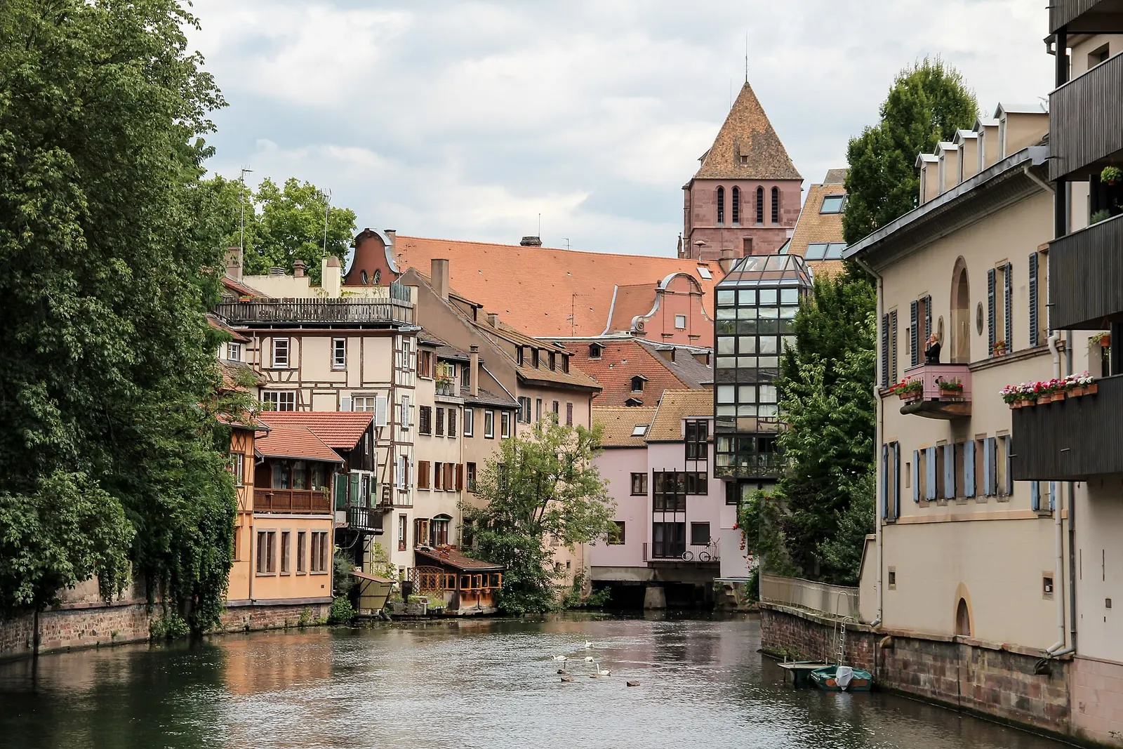 Deux personnes sur un pont de la Petite France à Strasbourg, devant les maisons à colombages qui se reflètent dans l'Ill