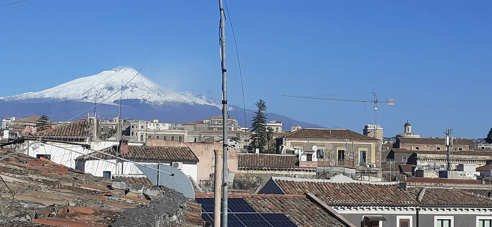 Una coppia passeggia in via Etnea a Catania al tramonto, con l'Etna sullo sfondo in fondo alla strada