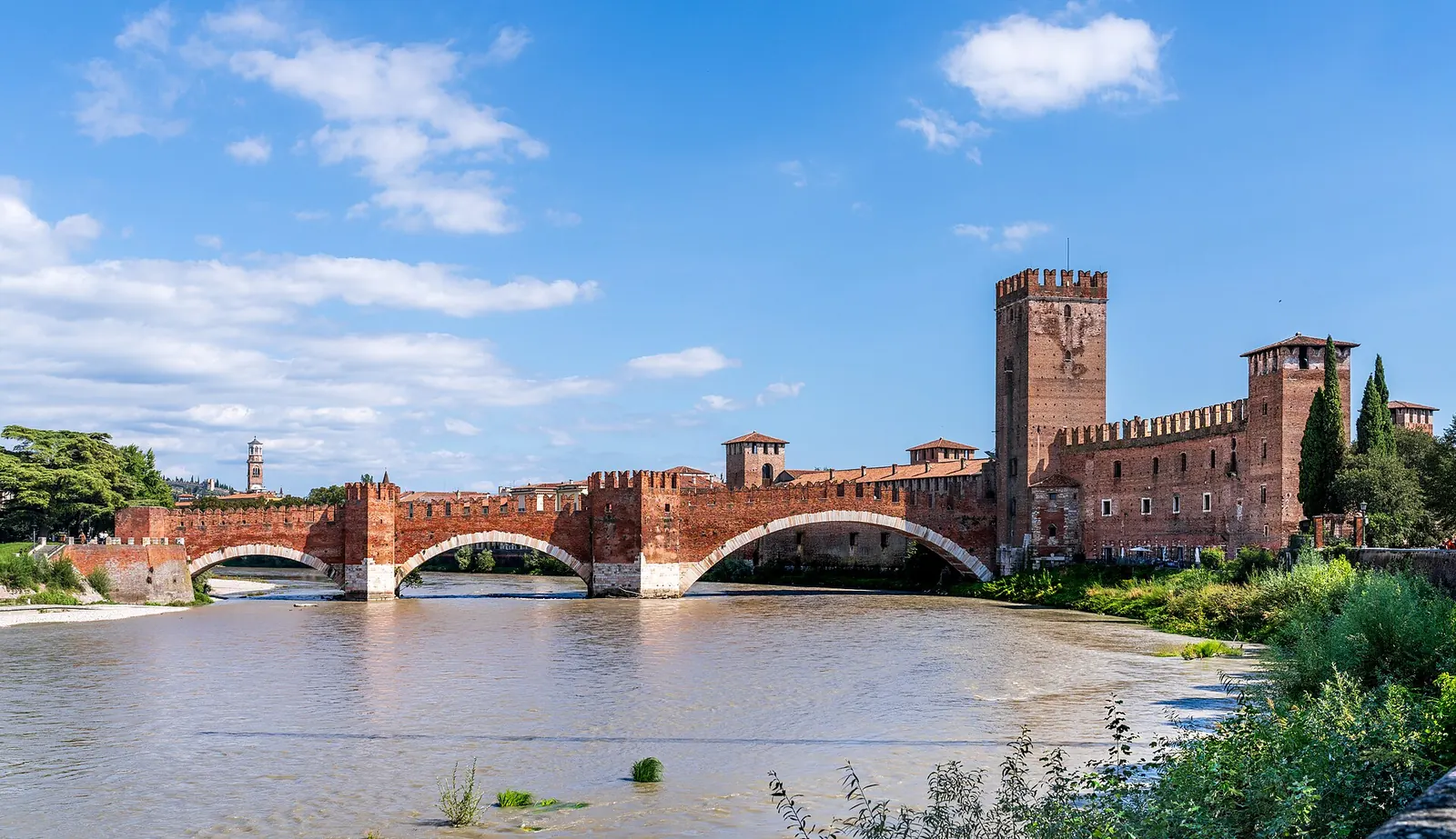 Una coppia si affaccia sull'Adige da Castel San Pietro al tramonto, con i tetti e i campanili di Verona sullo sfondo
