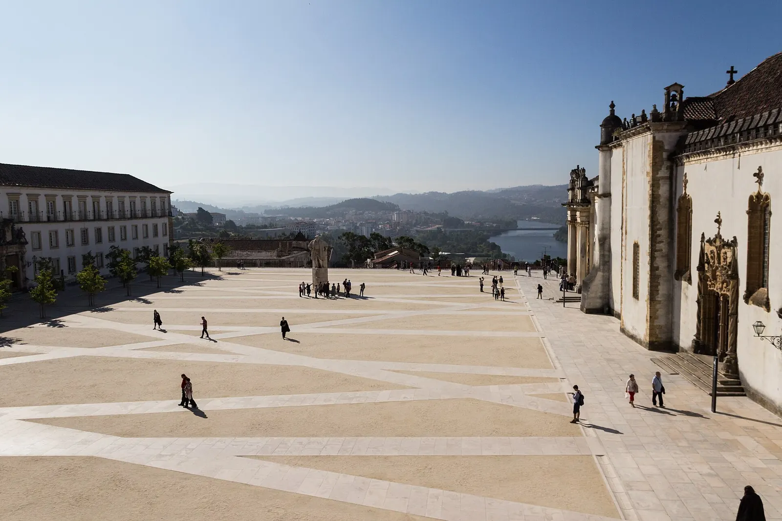 Casal a atravessar a ponte pedonal sobre o Mondego, com a Alta de Coimbra e a torre da Universidade ao fundo