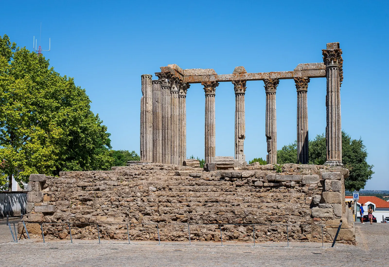 Casal a passear junto ao Templo Romano de Évora ao fim da tarde, com a luz dourada nas colunas