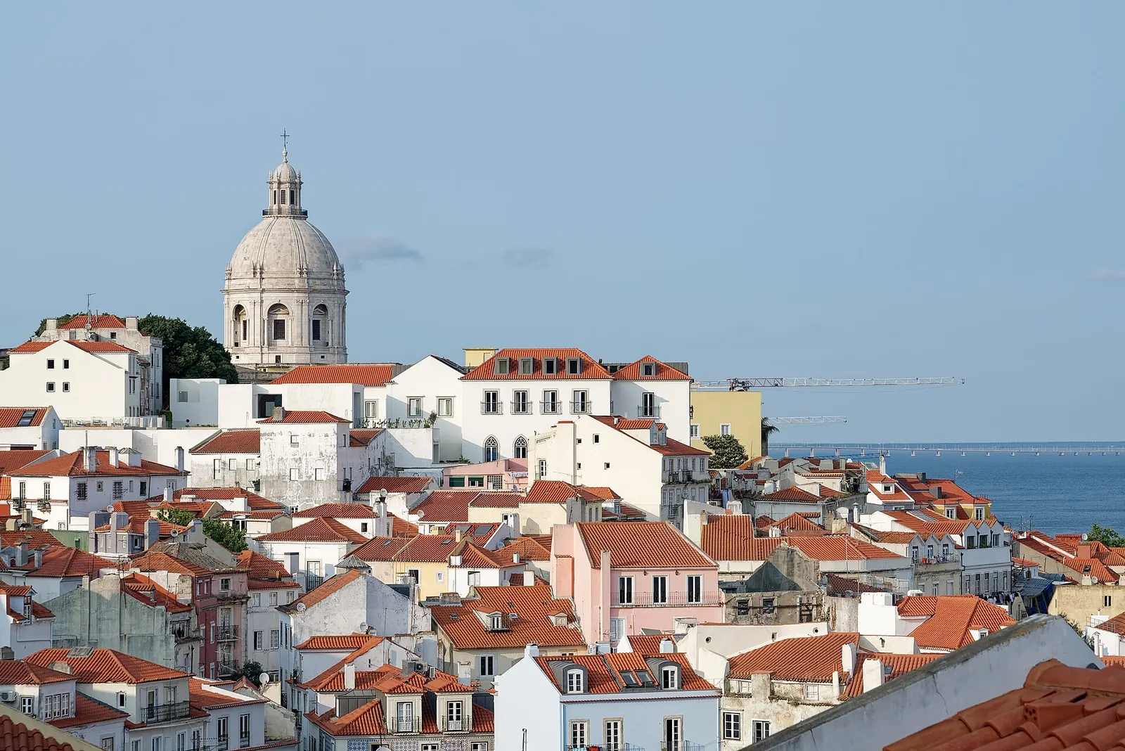 Casal num miradouro de Lisboa ao pôr do sol, com os telhados de Alfama e o Tejo ao fundo