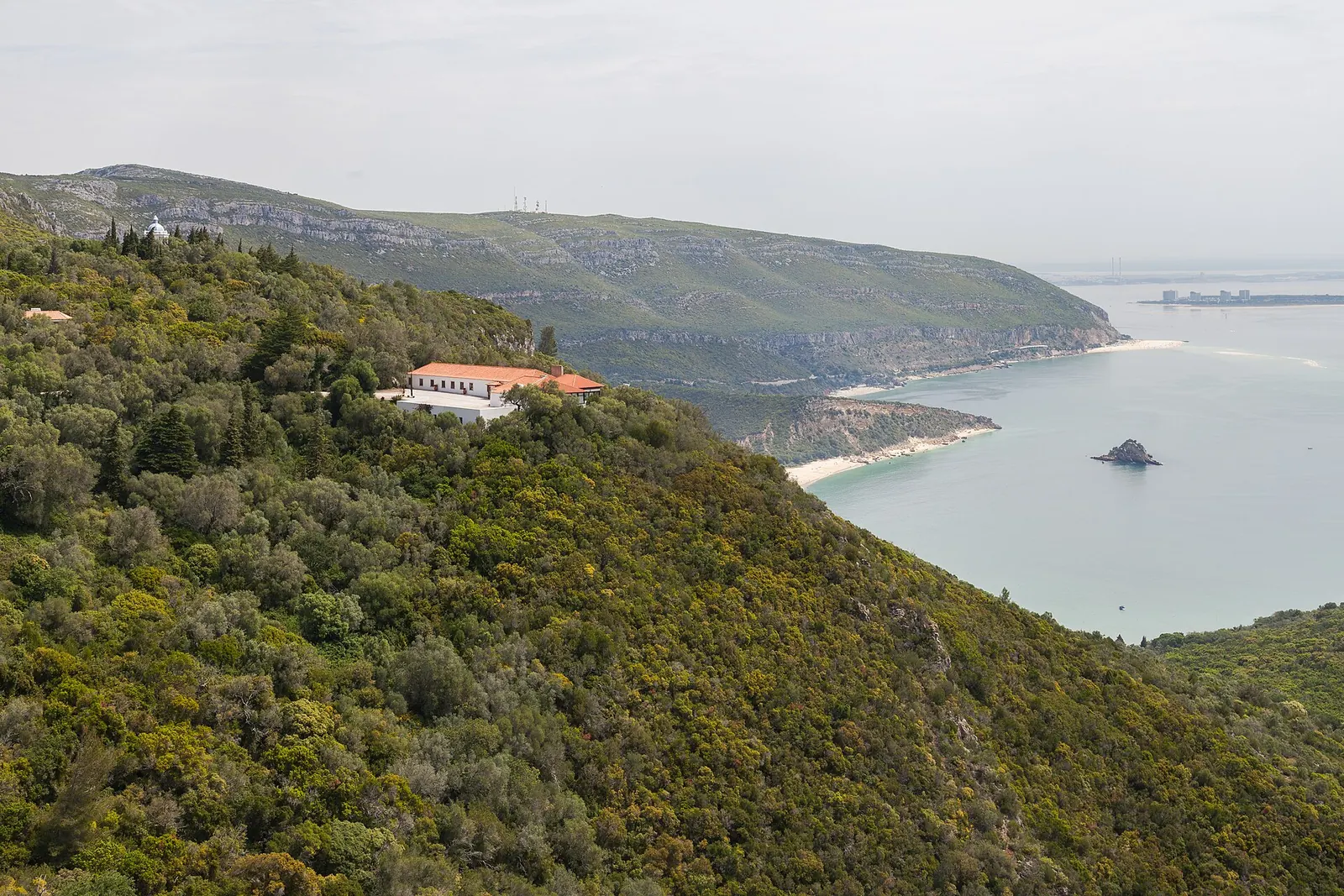 Casal num miradouro da serra da Arrábida, com o mar azul e a península de Tróia ao fundo